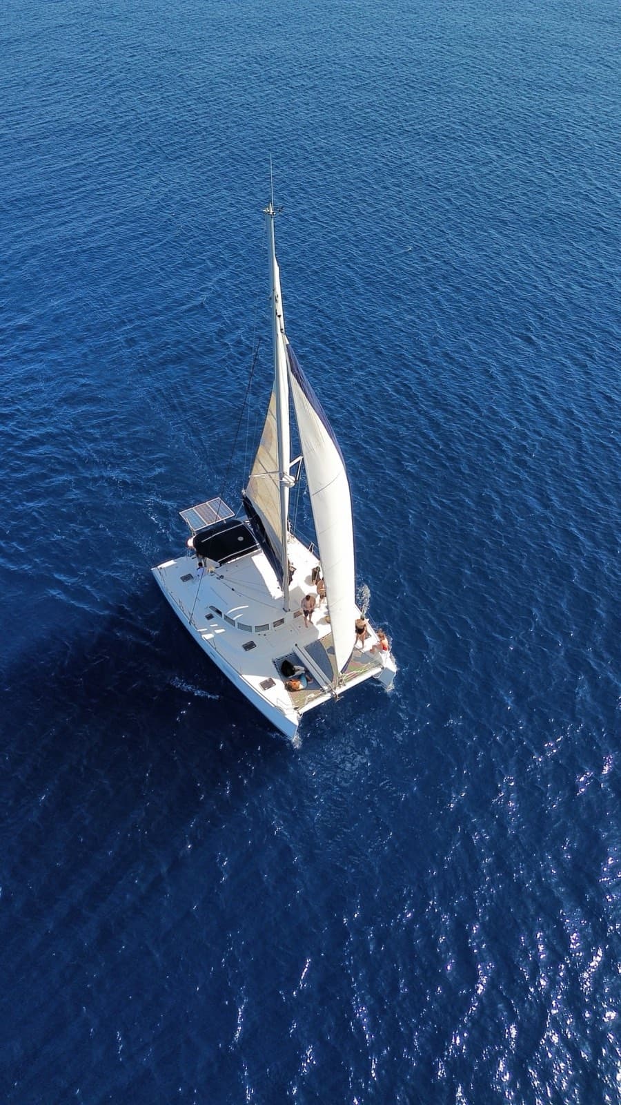 Gente en las redes y la cubierta de un catamarán, vista desde arriba